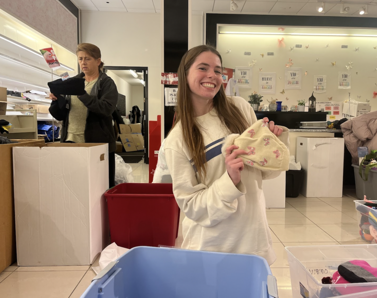 Viktoria Higgins, ‘25, poses with a donated girls’ winter hat. Winter gear, including hats, gloves and coats made up the largest donation groups, with Higgins sorting over 200 children’s hats on the Thursday before the event. Photo by Sabrina Roach, ‘25.
